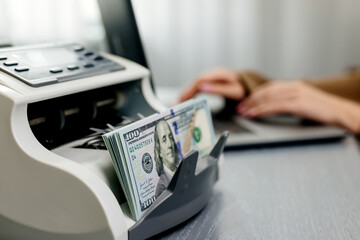 close-up of hands counting us dollar bills in an automatic cash counter. ideal for financial, bankin