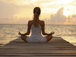 © VisionalMedia - Young woman practicing yoga at sunrise on a wooden pier by the sea