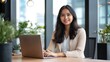 © Leli - A beautiful Asian businesswoman works intently on her laptop in a vibrant office
