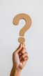 © olga_demina - Hand holding a wooden question mark on a plain white background. Minimalistic and symbolic image representing inquiry, curiosity, and knowledge.