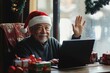 © Halina Berah - On his home computer, a senior biracial man is making a Christmas video call in a Santa hat while he is enjoying the holiday season