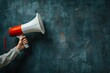 © raquel - Woman hand holding a megaphone on blue background with copy space