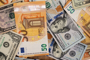 Poster - Euro banknotes with dollar bills scattered about table demonstrate concept of exchange rate of currencies influencing each other due to changes in global economics