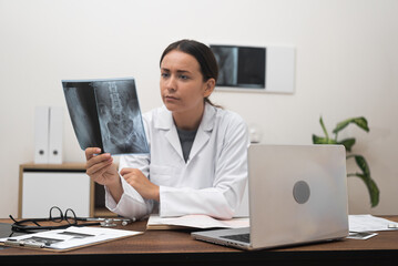 Poster - computer-equipped table, an orthopedic doctor examines patient X-ray films scans, showcasing the integration of online medicine
