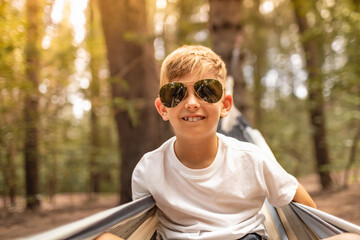 Portrait of cute little blond boy outdoors wearing sunglasses 