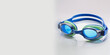 © Iaroslav - A pair of blue swimming goggles on a clean white surface. The goggles are positioned to show off their sleek design, while the background highlights their color.
