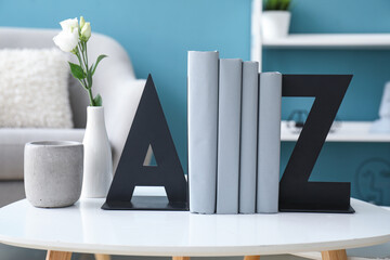 Stylish holder for books with vase of roses on table in room