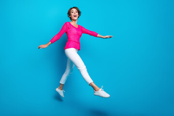 Wall Mural - Full length photo of funky sweet lady dressed pink knitted shirt jumping high walking empty space isolated blue color background