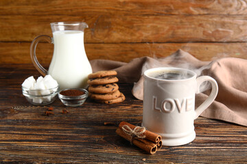 Cup of tasty coffee with cinnamon on wooden background