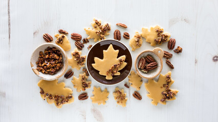 Wall Mural - Different shapes of maple pecan shortbread cookies scattered around with pecans.