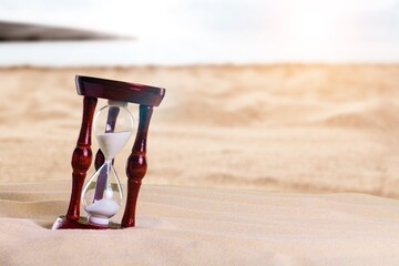 Antique sandglass in the sand on sea beach.