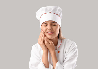 Sticker - Young female chef suffering from tooth ache on grey background