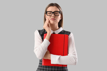 Canvas Print - Young businesswoman with red office folder suffering from tooth ache on grey background