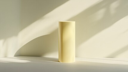 Wall Mural - A tall yellow vase sits on a white surface, casting a shadow on the wall