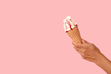 Wall Mural - Female hand with sweet ice-cream in waffle cone on pink background