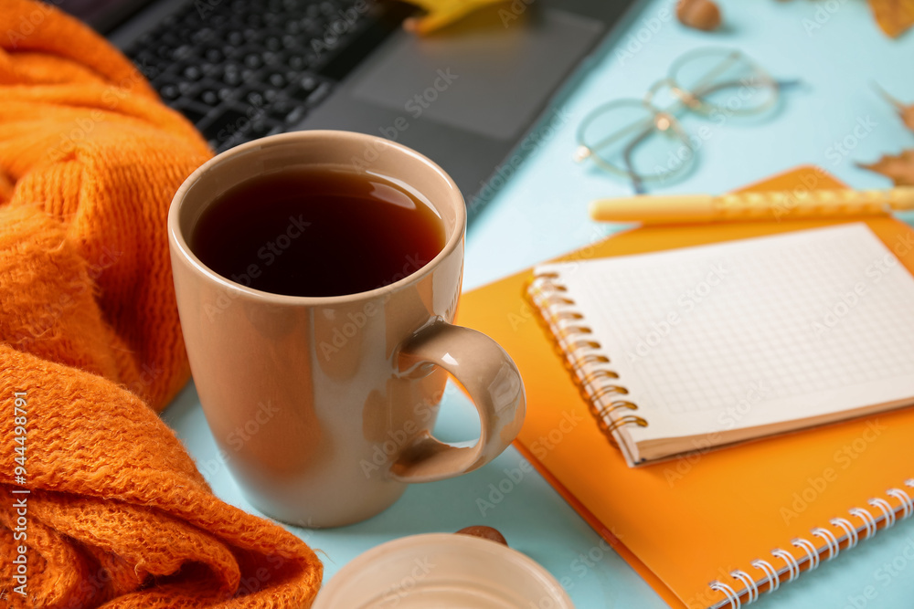 Cup of tea, notebooks and scarf on color background