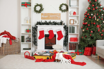 Poster - Interior of living room with Christmas tree, fireplace and open suitcase