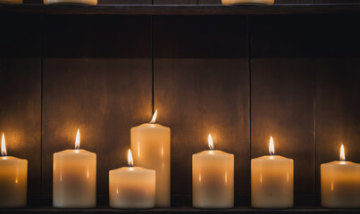 Seven candles are lit on a wooden shelf, casting a warm glow