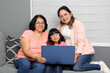 © Arlette - Three generations brunette latina grandmother, mom and daughter with glasses are surprised and excited while using laptop to shop with discounts and promotions
