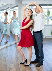 Wall Mural - Guy and girl in stage costumes, under guidance of mentor, practice boogie woogie in choreographic studio. Ballet dancers during personal training session. Professional rendering of dance entertainment