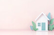 © Weerapat - A charming paper house model surrounded by leafy plants, set against a soft pastel background for a cozy ambiance.