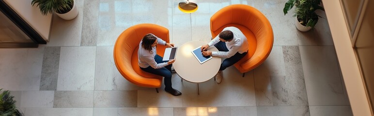 Poster - Business professionals seated in orange chairs discussing ideas at a round table in a modern office during daytime