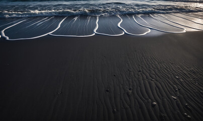 Waves gently lap at the black sand beach, creating a beautiful pattern