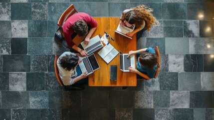 Poster - A group of students collaborating on laptops at a table in a modern study space during the afternoon