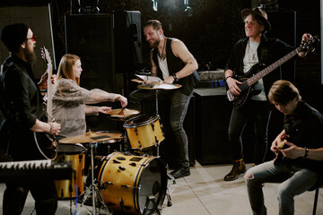 Wide shot of group of cheerful men and woman getting ready for rehearsal tuning musical instruments