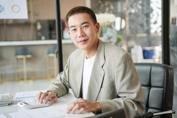 Smiling young Asian businessman in modern office. handsome asian man happy and friendly while working success job