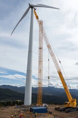 Wall Mural - A crane installs a wind turbine hub onto the tower. The site features various construction tools and equipment