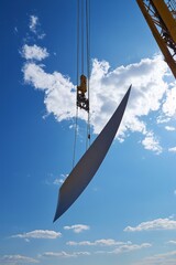 Wall Mural - A wind turbine tower section is lifted by a crane. Other construction equipment and turbines are in view