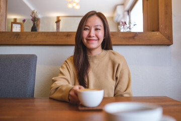 Wall Mural - Portrait image of a young woman holding and drinking coffee with friend