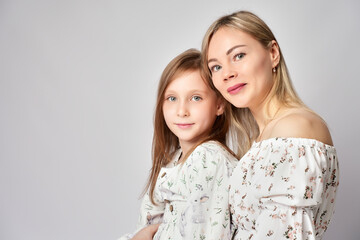 Portrait of young mother and daughter. Happy woman with child girl. Family portrait on a white background