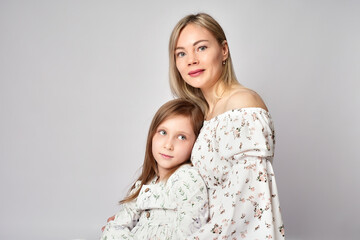 Wall Mural - Portrait of young mother and daughter. Happy woman with child girl. Family portrait on a white background