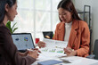 © crizzystudio - Team of Asian businesswomen analyze and brainstorm using calculators Financial data pointing hand on sheet. Graph chart showing income on laptop. Concept of teamwork process, growth.