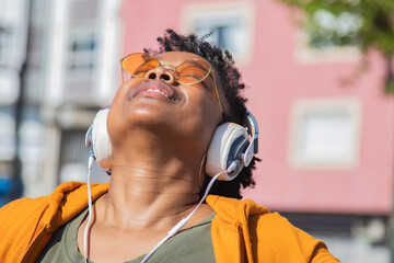 Wall Mural - urban woman enjoying free time with headphones on the street