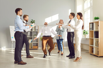 Office workers, colleagues and coworkers, are playing the limbo game and dancing at an office party event. The atmosphere is festive as they celebrate together, showcasing team spirit and group fun.