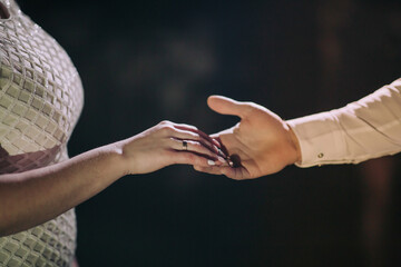 A couple is holding hands, with one of them wearing a wedding ring. Concept of love and commitment between the two people