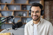 © Tetiana - Smiling man in headphones recording podcast in studio with microphone, enjoying conversation and audio production