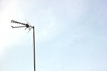 during the day and the sky is not so blue there is a television antenna standing upright