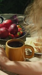 Wall Mural - Vertical video. Woman pouring tea into ceramic mug on wooden garden table.