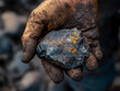 © elbanco - Close up of a hand holding a raw piece of iron ore.