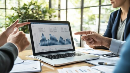 Poster - People in a business meeting analyze data graphs displayed on a laptop screen, indicating discussion and collaboration. The bright, modern setting enhances productivity.