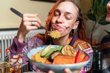 This is Delicious! Woman eating a home made vegan dish. Her and her friends have cooked creole aubergines and quinoa with sweet potatoes, peppers and avocado puree. She has her eyes closed and is enjo