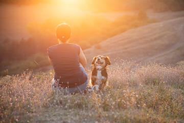 Wall Mural - Young woman with her dog watching the sunset