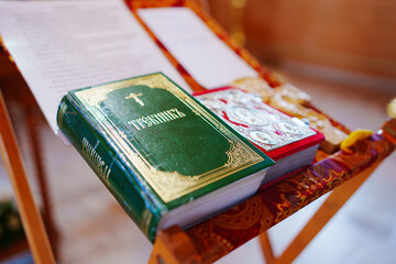 A prayer book with an inscription in Old Russian on the table for the priest at a church service. Christian faith and traditions. baptism