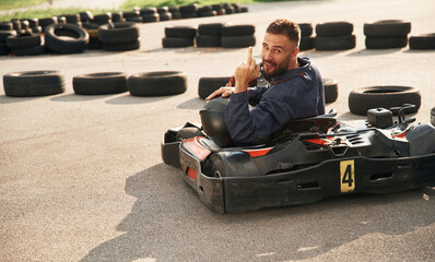 Wall Mural - Looks behind while riding. Man is outdoors, kart racing conception