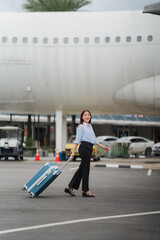 Ready for Takeoff: A young woman, radiating excitement, strides confidently across the airport tarmac, her blue suitcase trailing behind her, symbolizing the start of an adventure. 