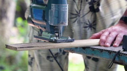 Wall Mural - A worker cuts a board with a jigsaw